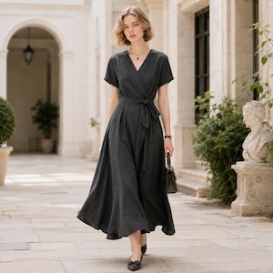Puede incluir: Un vestido cruzado midi de color gris carbón con mangas cortas, escote en V y un cinturón de tela a juego en la cintura. El vestido presenta una tela texturizada, una falda acampanada y se combina con un bolso oscuro pequeño y zapatos planos.