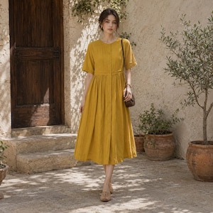 May include: A mustard yellow midi dress featuring short sleeves, a round neckline, and a full-length button-down front closure. The garment has a fitted bodice with a defined waistline that transitions into a pleated, flowing skirt silhouette.