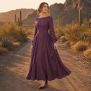 Puede incluir: Un vestido largo hasta el suelo de color morado ciruela intenso con mangas largas. La prenda presenta un corpi&ntilde;o ajustado, un escote redondeado y una falda amplia y plisada que cae hacia el dobladillo. Las mangas tienen pu&ntilde;os fruncidos.