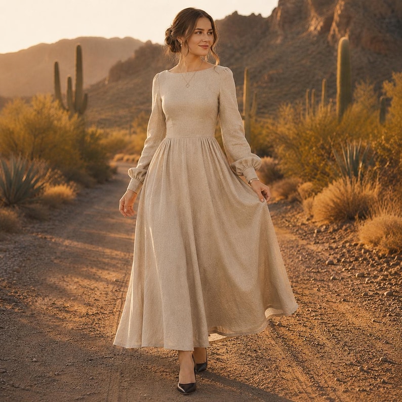 Puede incluir: Un vestido beige de manga larga que llega hasta el suelo, con un corpi&ntilde;o ajustado, cuello redondo y una falda amplia y fluida. El vestido presenta mangas con pu&ntilde;os y un dise&ntilde;o de tela de color s&oacute;lido que llega hasta los tobillos.