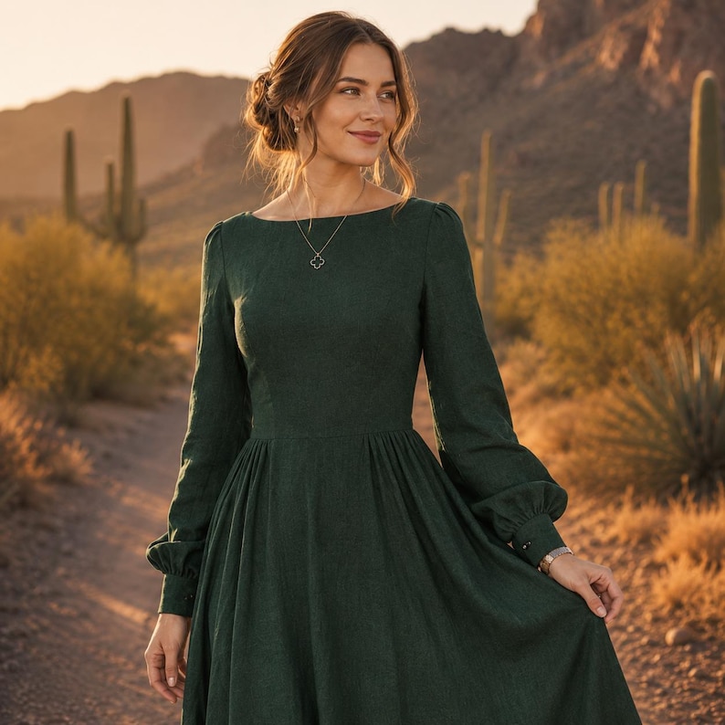 Puede incluir: Un vestido de color verde oscuro de manga larga con corpi&ntilde;o ajustado, cintura entallada y falda amplia y fluida. El vestido presenta un escote barco, mangas con pu&ntilde;os abotonados y un tejido texturizado, junto a un colgante en forma de tr&eacute;bol.