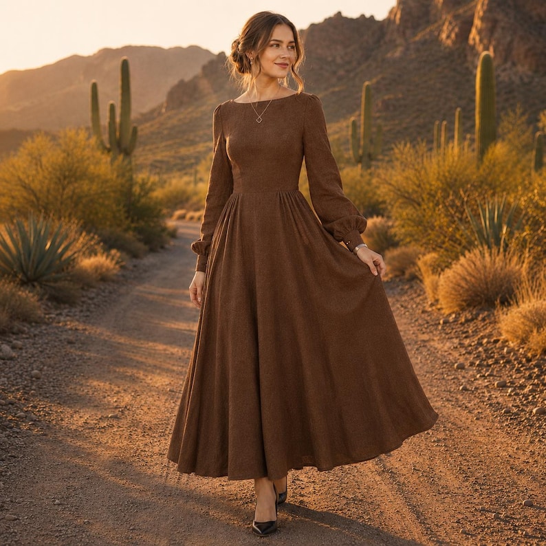 Puede incluir: Un vestido largo de color marr&oacute;n con mangas largas, cuerpo ajustado, cintura entallada y una falda amplia y fluida que llega hasta los tobillos. El vestido presenta un cuello redondo sencillo y mangas largas con pu&ntilde;os abotonados.