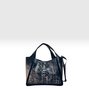 Può includere: Una borsa a mano nera e argento metallizzato con un motivo testurizzato a pelle di serpente. La borsa ha una forma trapezoidale strutturata con due manici superiori e una tracolla laterale. Il pannello frontale mostra un design a scaglie.