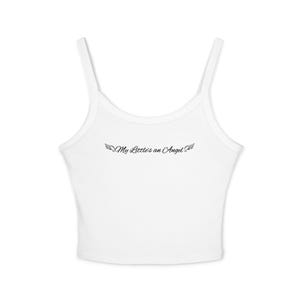 Op de afbeelding: Een witte mouwloze crop top met dunne schouderbandjes en een ronde halslijn. In het midden van de borst staat zwarte cursieve tekst met de tekst My Little's an Angel, geflankeerd door kleine, gedetailleerde zwarte engelvleugels aan weerszijden.