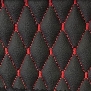 Op de afbeelding: Een zwart getextureerd materiaal met een gewatteerd ruitpatroon gestikt met felrood garen. De stof toont een herhalend geometrisch ontwerp met verhoogde, gewatteerde secties die worden gevormd door de rode lijnen over het donkere oppervlak.
