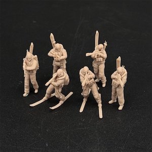 May include: A set of six unpainted beige miniature figurines depicting soldiers equipped for winter warfare. Each figure wears tactical gear, carries a rifle, and has skis attached to their feet or strapped to their backs in various poses.