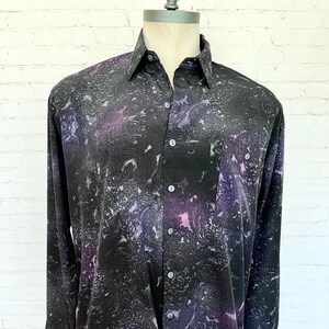 May include: A long-sleeved button-down shirt with a black and purple abstract print. The shirt has a classic collar and a single chest pocket.