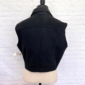 May include: A black denim vest with a button-up front and a classic style.