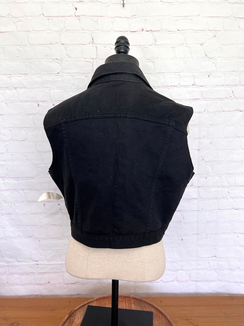 May include: A black denim vest with a button-up front and a classic style.