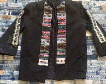 May include: A black jacket with colorful embroidered trim on the sleeves and front. The trim features geometric patterns in shades of red, green, blue, yellow, and white.