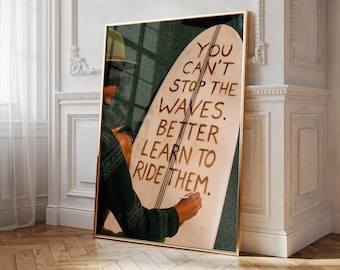Puede incluir: Una impresión de arte mural vertical enmarcada que muestra a una persona con una camisa de manga larga verde oscuro sosteniendo una tabla de surf. La tabla muestra el texto: YOU CAN'T STOP THE WAVES. BETTER LEARN TO RIDE THEM. Marco dorado.