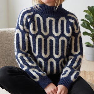 May include: A long-sleeved mock neck sweater featuring a fuzzy texture and a repeating cream-colored wavy line pattern set against a deep navy blue background. The knit garment has ribbed cuffs and a ribbed neckline, providing a consistent fit.