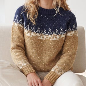 Può includere: Un maglione in maglia a maniche lunghe con scollo rotondo e polsini a coste. La parte superiore del petto e le spalle sono blu navy scuro, mentre la parte inferiore del corpo e le maniche sono color marrone chiaro. Un motivo geometrico bianco.