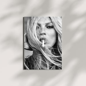 Könnte beinhalten: Ein schwarz-weißes fotografisches Porträt einer Person mit langem, glattem Haar, das das Gesicht teilweise verdeckt. Die Person hält eine Zigarette zwischen den Lippen. Das Bild zeichnet sich durch kontrastreiche Beleuchtung und eine monochrome Farbpalette aus.
