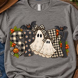 May include: A heather grey t-shirt featuring the word SPOOKY in large letters. The letters are decorated with black and white buffalo plaid, black fabric with white daisies, and two white ghost figures wearing plaid bows. Bats, orange berries, and a pumpkin are included.