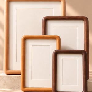 Peut inclure: Un ensemble de quatre cadres photo rectangulaires aux coins arrondis, présentant des tons de bois variés allant du brun clair au brun foncé. Chaque cadre comprend un passe-partout blanc, créant un aspect épuré pour exposer des images.