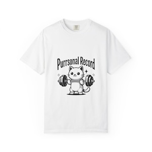 Könnte beinhalten: Ein weißes kurzärmeliges T-Shirt mit einer schwarzen Grafik einer Cartoon-Katze, die eine Langhantel hebt. Über der Katze steht der Text Purrsonal Record in einer fetten, geschwungenen Schriftart mittig auf der Brust des Kleidungsstücks.