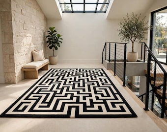 May include: A rectangular area rug featuring a high-contrast black and white geometric maze pattern. The design consists of interconnected lines and right-angled paths that span the entire surface of the rug, creating a complex, repeating labyrinth motif.