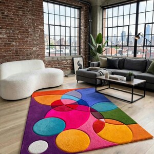 May include: A rectangular area rug featuring a vibrant, multi-colored geometric pattern of overlapping circles and semi-circles in shades of hot pink, orange, purple, teal, green, and white, with a soft, plush texture covering the floor surface.