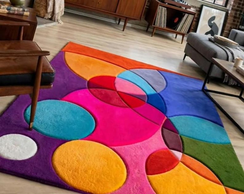 May include: A rectangular area rug featuring a vibrant, multi-colored geometric pattern composed of overlapping circles and semi-circles in shades of hot pink, orange, teal, purple, blue, red, green, and white with a soft, plush texture.