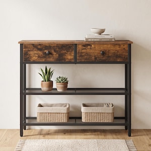 May include: A console table with a dark brown wood-grain top and two drawers, supported by a black metal frame. It features two open shelves holding two potted plants and two woven baskets. A small bowl and two books sit on the top surface.