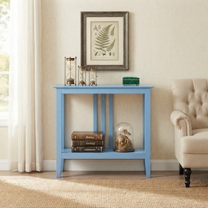May include: A light blue console table with a rectangular top and a lower shelf. The table features three vertical slats connecting the top to the shelf. On the table sit three hourglasses, a framed fern print, and a green box.
