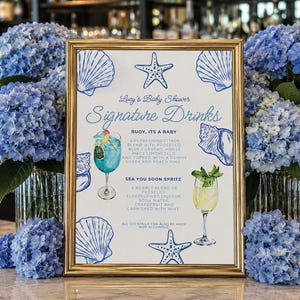 Pode incluir: Uma placa com moldura dourada intitulada Lucy's Baby Shower Signature Drinks, com ilustrações azuis de conchas e estrelas do mar. Lista dois coquetéis, Buoy, Its A Baby e Sea You Soon Spritz, com descrições de ingredientes e guarnições.