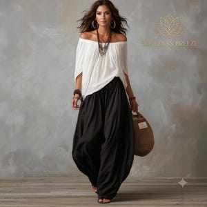 May include: An off-the-shoulder white blouse with loose sleeves paired with black wide-leg trousers. The outfit includes a layered necklace, multiple bracelets, and a brown woven bag. The text BOHEMIAN BREEZE EST 2023 is visible in the upper right corner.