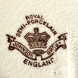 May include: Close-up of a white ceramic surface with a cracked texture. The image features a brown emblem with the words "Royal Semi-Porcelain" and "Johnson Bros England" surrounding a crown.