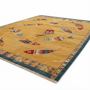 May include: A rectangular area rug with a golden-yellow background featuring multiple stylized fish motifs in various colors including red, blue, and brown. The rug has a dark blue border with a repeating geometric pattern and white fringe edges.