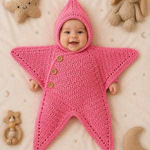 May include: A bright pink crocheted star-shaped wearable blanket with a pointed hood and three light brown wooden buttons along the side. The garment features a textured stitch pattern and extends into five points, covering the torso and arms.