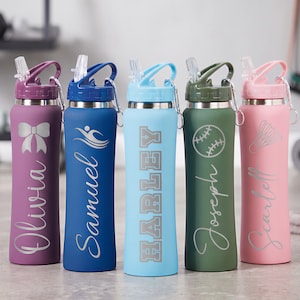 May include: Five cylindrical water bottles with straws and carabiners in purple, blue, light blue, olive green, and pink. Each bottle features a unique laser-engraved design and name: Olivia with a bow, Samuel with a swimmer, Harley, Joseph with a baseball, and Scarlett with a shuttlecock.