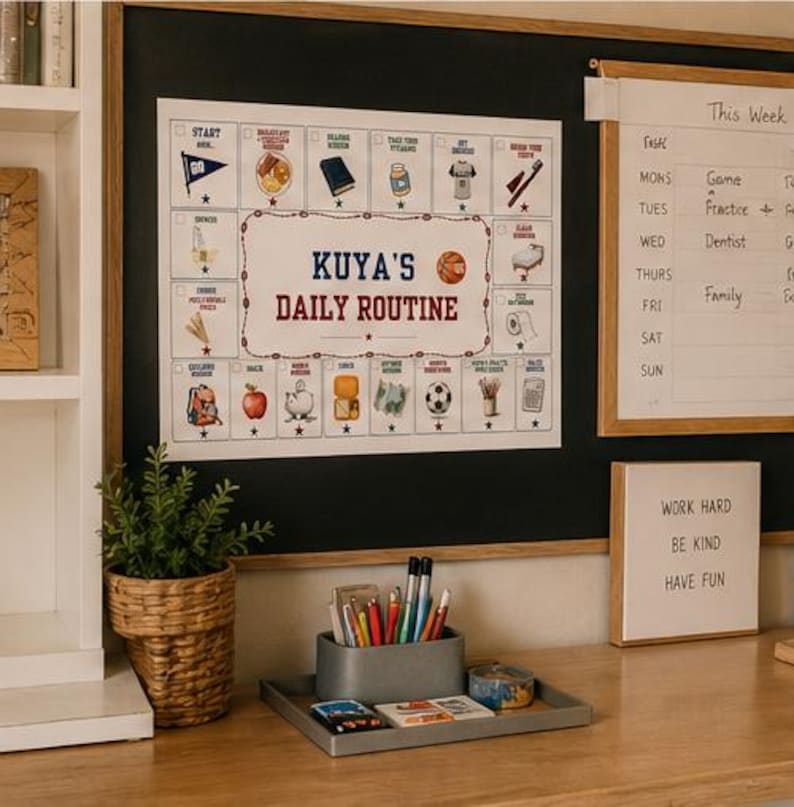 May include: A white daily routine chart with the text Kuya's Daily Routine, featuring colourful illustrations of daily tasks, a basketball, and checkboxes. The chart is displayed on a black board next to a weekly planner and a desk organiser with pens.
