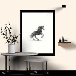 May include: A framed wall art print featuring a black ink scribble-style illustration of a rearing horse on a white background. The artwork is displayed in a black frame, positioned above two round marble-topped tables with metal legs.