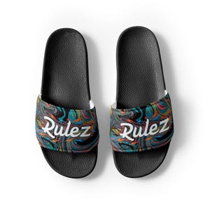 May include: A pair of black slide sandals featuring a textured footbed and a wide strap across the top. The strap displays a vibrant, multicolored marbled pattern in shades of blue, orange, and black, with the word Rulez printed in white.