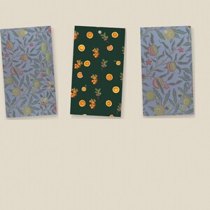 May include: Three rectangular gift tags with rounded top corners. The two outer tags feature a blue background with a repeating pattern of green leaves and round fruit. The center tag has a dark green background with orange fruit slices.