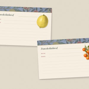 May include: Two cream-colored recipe cards featuring a blue floral border at the top. Each card includes the printed text From the kitchen of, Recipe, and Makes, with lines for writing. One card displays a yellow lemon, the other a cluster of oranges.