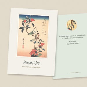 Op de afbeelding: Een gevouwen wenskaart met een illustratie in Japanse stijl van vogels op een bloeiende tak met de tekst Peace & Joy en With love from the Whitfields. De binnenzijde toont de tekst Wishing you a season of long dinners, lit candles and good company. With love, Caroline & James.