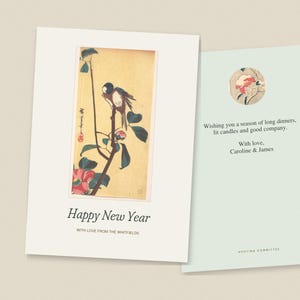 Op de afbeelding: Een gevouwen wenskaart met een illustratie van een vogel op een tak, de tekst Happy New Year en With love from the Whitfields. Een binnenpaneel toont een bloemencirkel, de tekst Wishing you a season of long dinners, lit candles and good company, With love, Caroline & James en Hosting Committee.