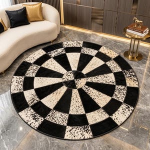May include: A circular area rug featuring a geometric pattern of alternating black solid panels and white panels with black speckled animal print. The rug is constructed from pieced segments arranged in a radial design with a central circular focal point.