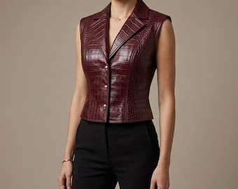 May include: A sleeveless vest in a deep burgundy color with a textured crocodile skin pattern. The garment features a notched lapel collar, a tailored fit, and a front button closure with four metallic buttons. It is paired with black trousers.