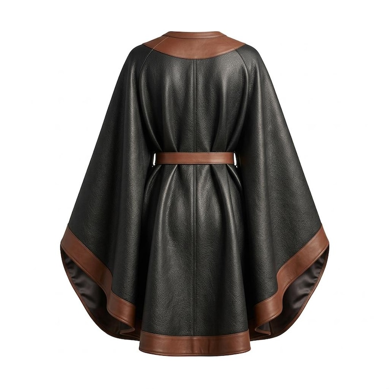 May include: A black cape with a textured finish, featuring a brown leather-look collar and a matching brown leather-look hemline. The garment includes a brown leather-look belt at the waist, creating a gathered, draped silhouette with wide sleeves.