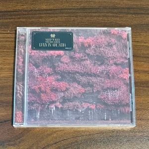 May include: A clear plastic CD jewel case featuring a dark, moody forest scene with vibrant pink foliage. A black rectangular sticker in the top left corner displays the text: Sleep Token, The New Album, Even In Arcadia.