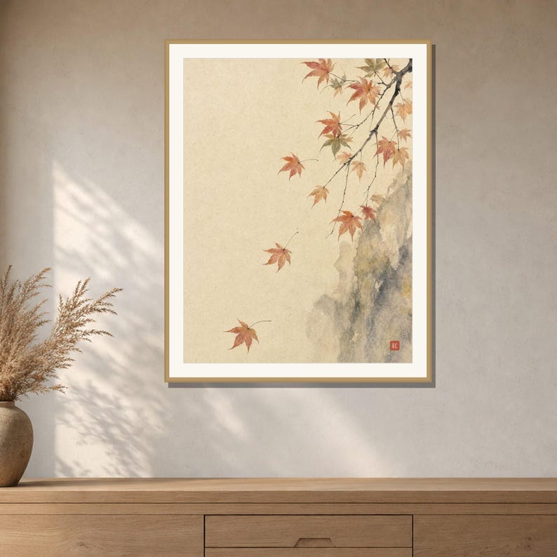 May include: A framed wall art print featuring a watercolor painting of delicate maple branches with orange and red leaves falling against a light beige background, with a dark gray rock formation on the right and a small red square seal mark.