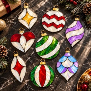 Puede incluir: Una colección de ocho adornos de vidrio tintado con diversas formas y colores, incluyendo acentos en rojo, verde, azul, morado y amarillo. Cada adorno tiene una tapa de metal dorado y una base blanca nacarada con patrones geométricos.
