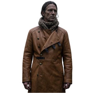 Peut inclure: Un manteau en cuir beige doté d'une fermeture croisée avec des boutons métalliques, des pattes de fermeture en cuir foncé et des détails gaufrés sur les poignets. Le manteau est porté avec une écharpe en grosse maille beige neutre.