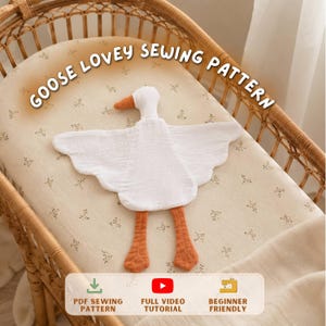Può includere: Un doudou oca in tessuto bianco con becco e zampe arancioni. Il testo GOOSE LOVEY SEWING PATTERN è arcuato sopra. In basso, icone per PDF SEWING PATTERN, FULL VIDEO TUTORIAL e BEGINNER FRIENDLY indicano un progetto di cucito digitale.