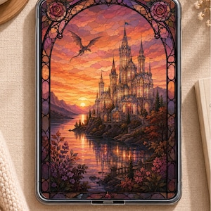 May include: A rectangular tablet displaying a digital illustration of a castle on a lakeshore at sunset, framed by a decorative stained glass arch with rose motifs. A dragon flies in the orange and purple sky above the illuminated castle structure.