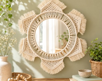 May include: A circular wall mirror framed by intricate off-white macrame cord woven into a six-pointed star shape. The design features detailed knot work and long, straight fringe edges surrounding the central glass mirror surface.