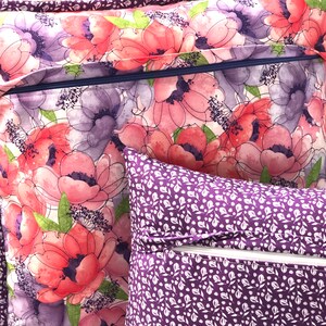 Puede incluir: Dos fundas de coj&iacute;n decorativas con cierres de cremallera. Una funda presenta un patr&oacute;n floral en tonos rosas, morados y verdes. La otra funda tiene un fondo morado con un patr&oacute;n floral blanco.